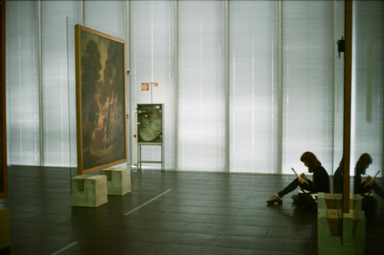 there is a young woman sitting on the floor in front of a picture