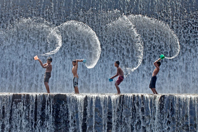 a group of people playing in water spray on top of a waterfall