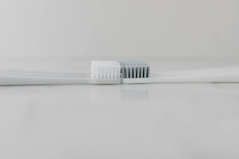 an empty white toothbrush against a pale colored background