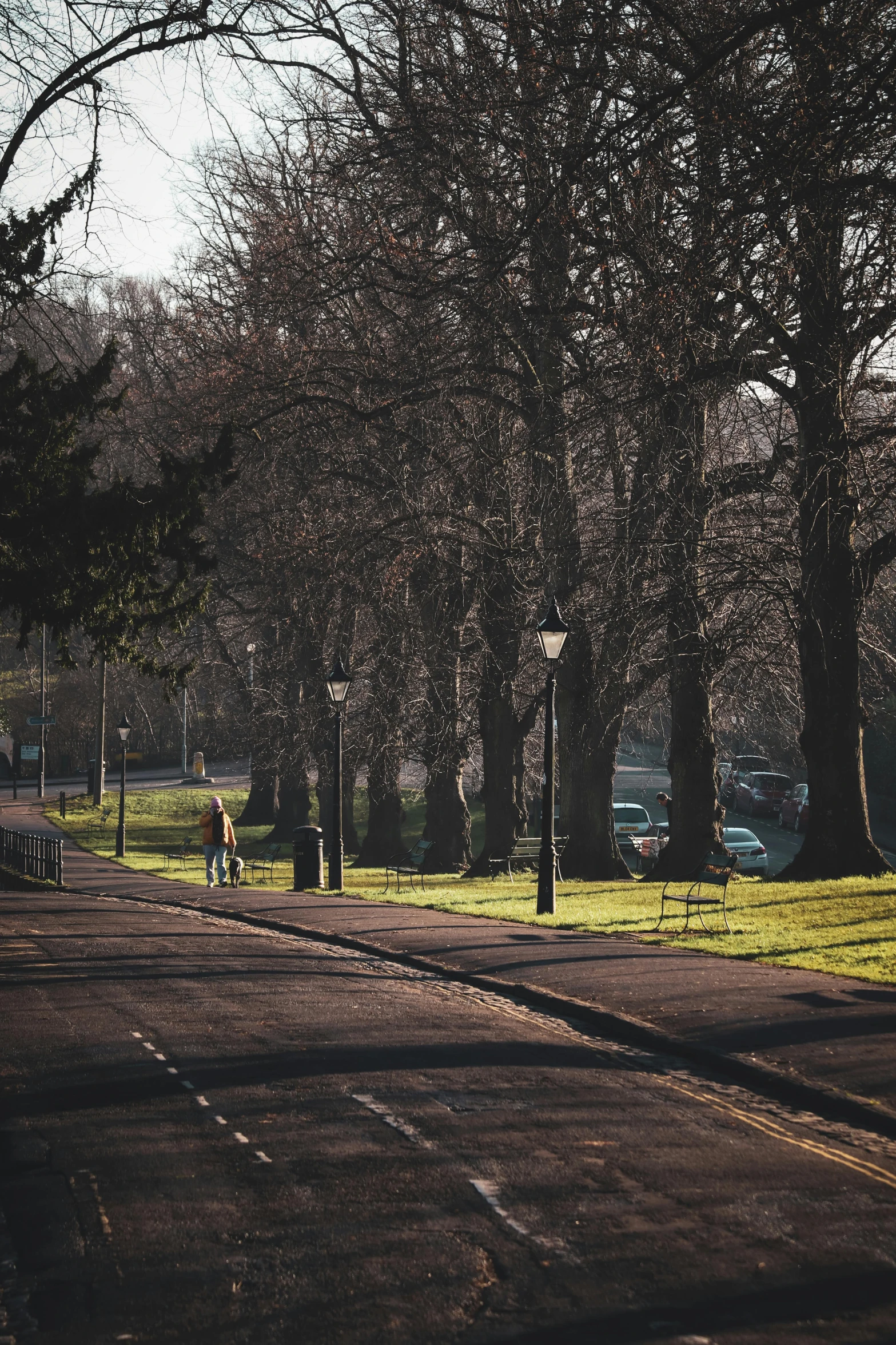 two people are walking down the path in the park