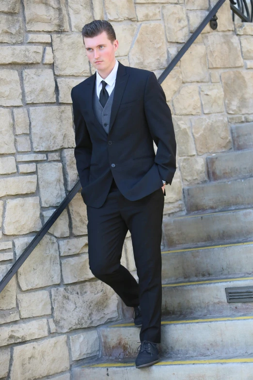 a young man in a suit poses on the stairs