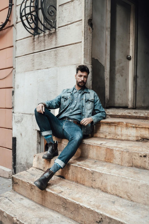 a man sitting on a step while wearing all denim