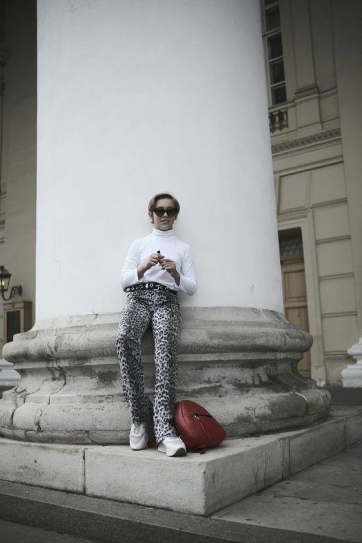 woman with red hand bag sitting outside of building