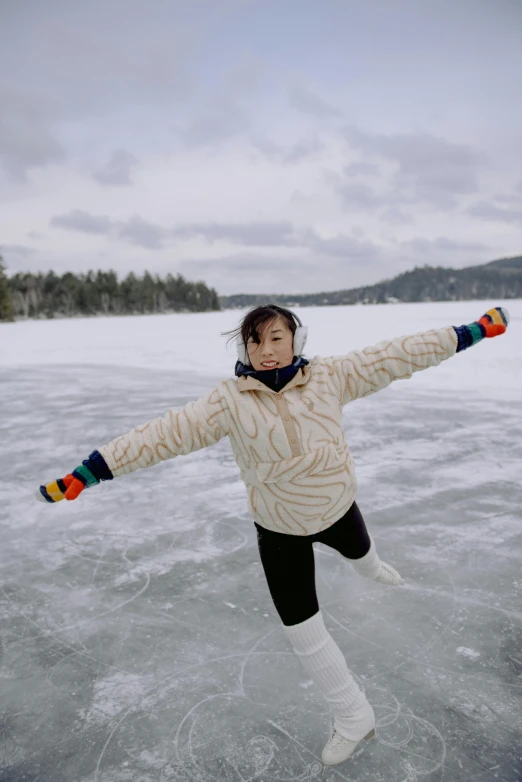 a woman holding her arms outstretched while skating on ice