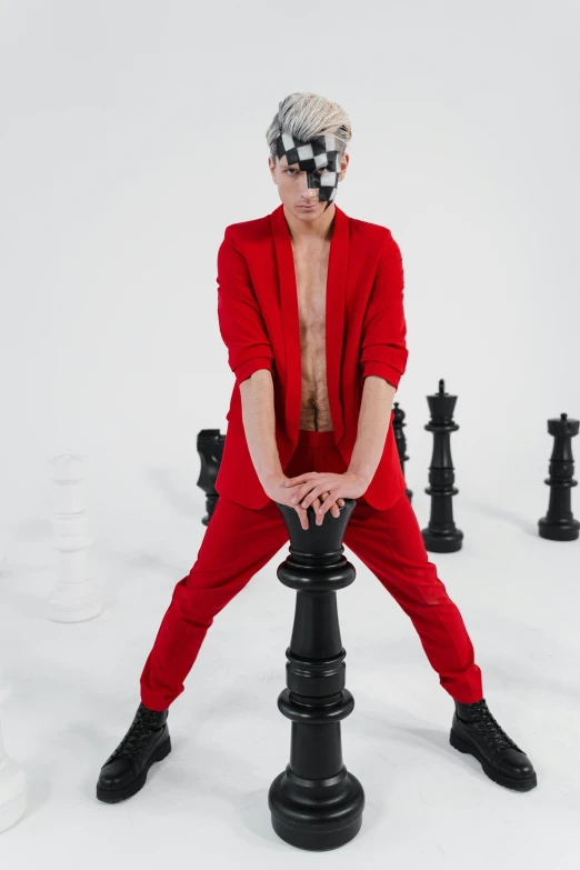 a male with a red suit is sitting on a black pole