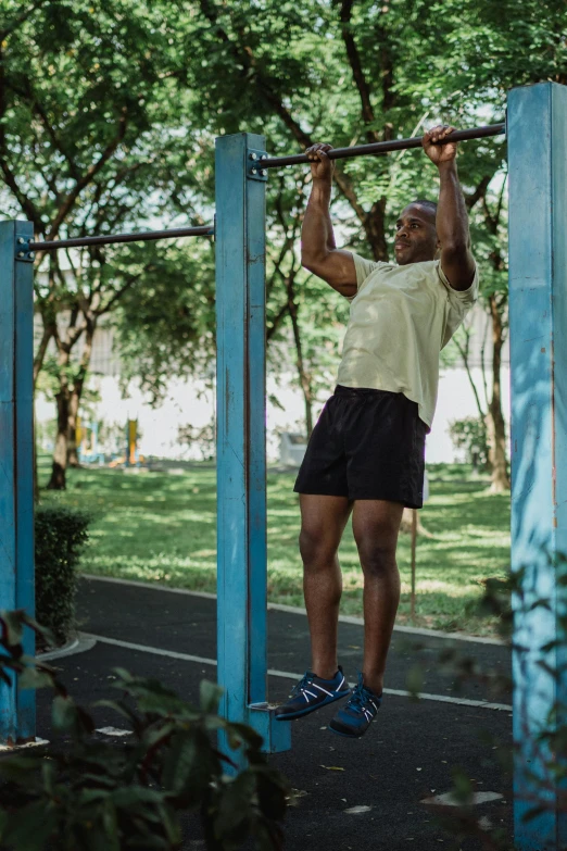 a man is doing pull ups in a park