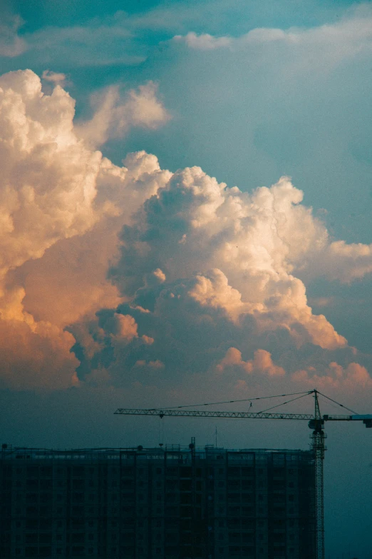 the sky is blue and cloudy and there are cranes on the building