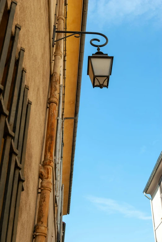 a street lamp with no lights attached to the side of an old building