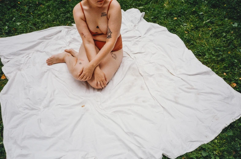 a woman sitting on top of a blanket in a field