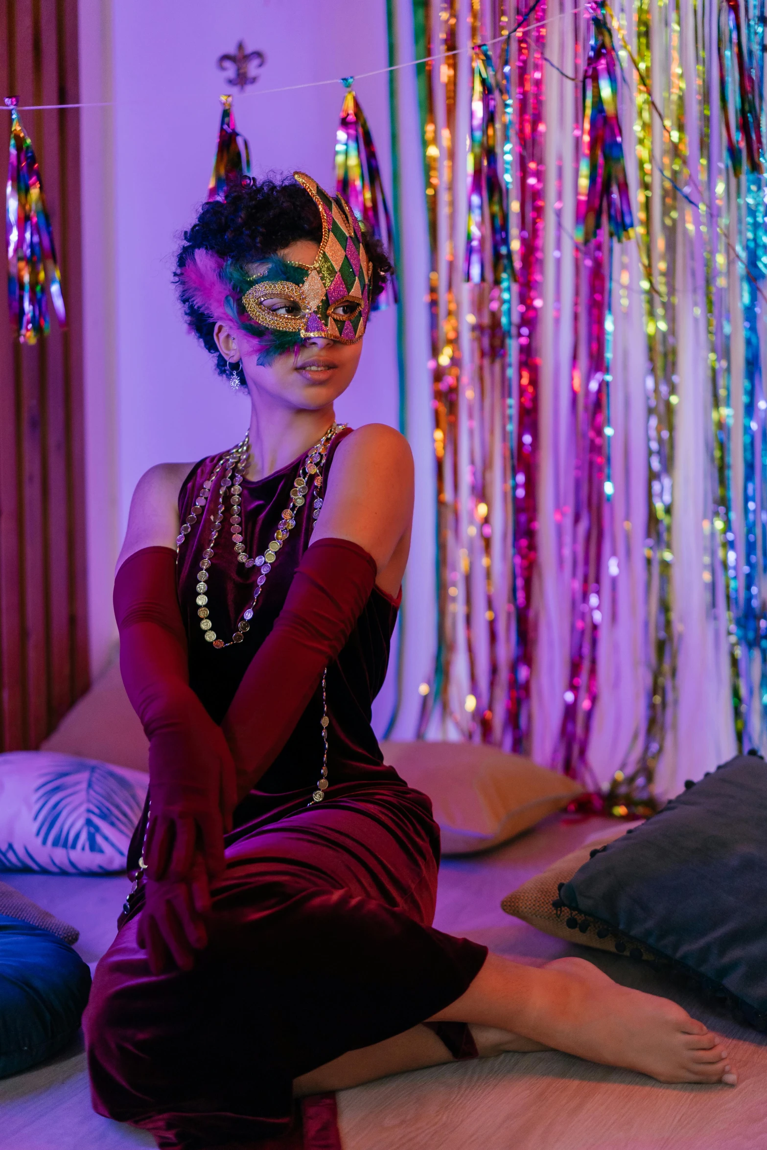 the woman is dressed in colorful masks and sitting on the floor