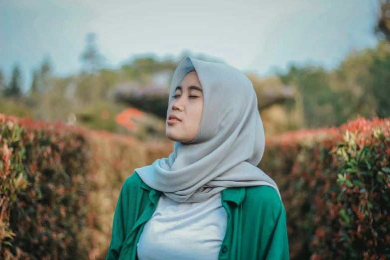 a woman with green clothing stands outside in the grass