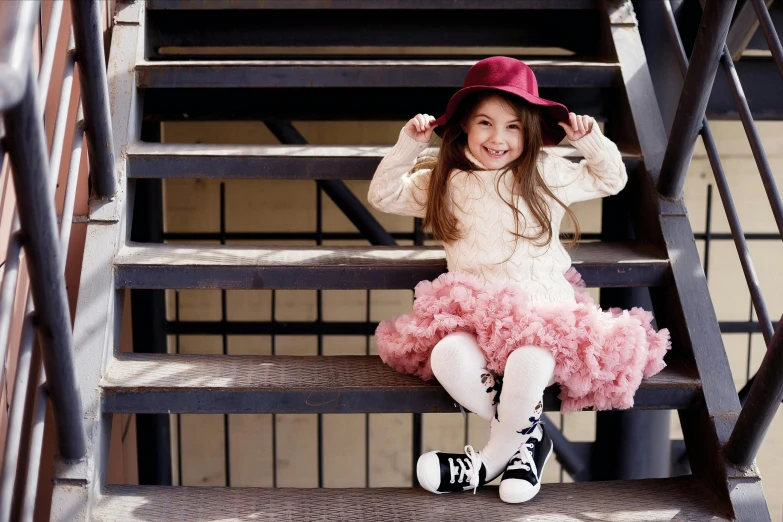 a  posing on some steps in a dress and a hat