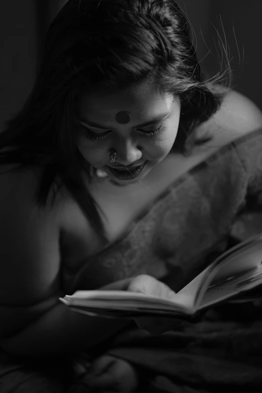 a woman laying in bed and reading a book