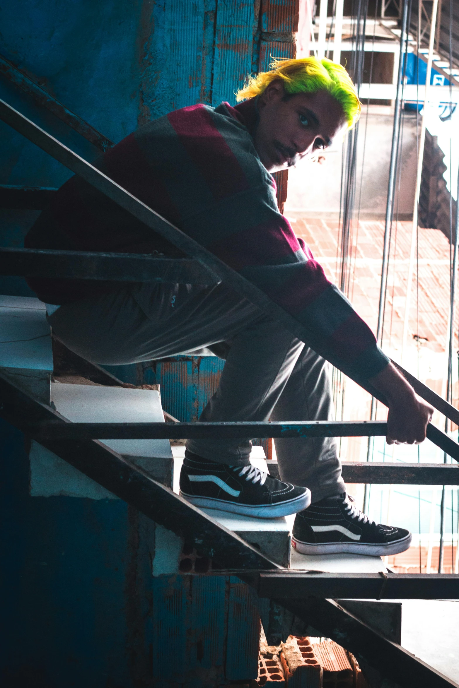 a man with a brightly colored wig and green hair sitting on some stairs