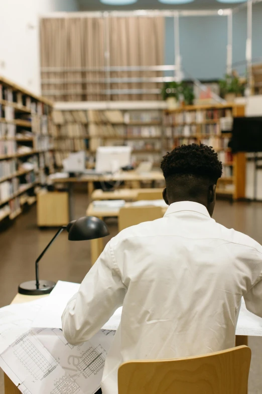 a man reading in an old liry surrounded by rows of books