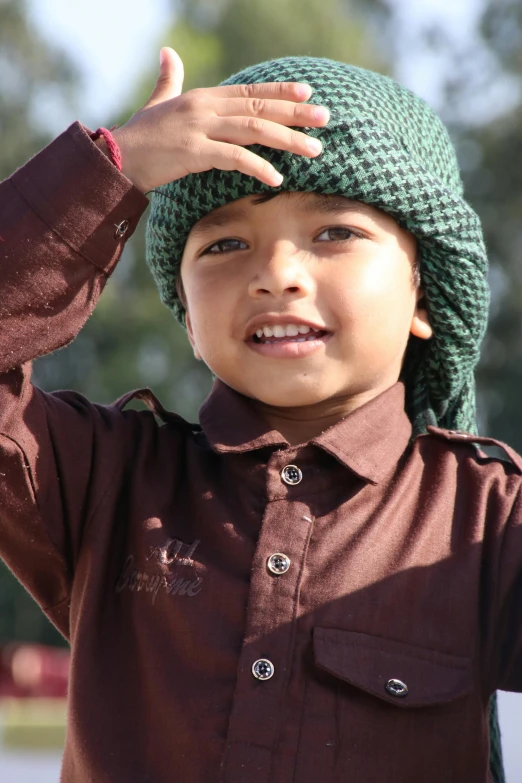 a boy has a green hat and his fingers up