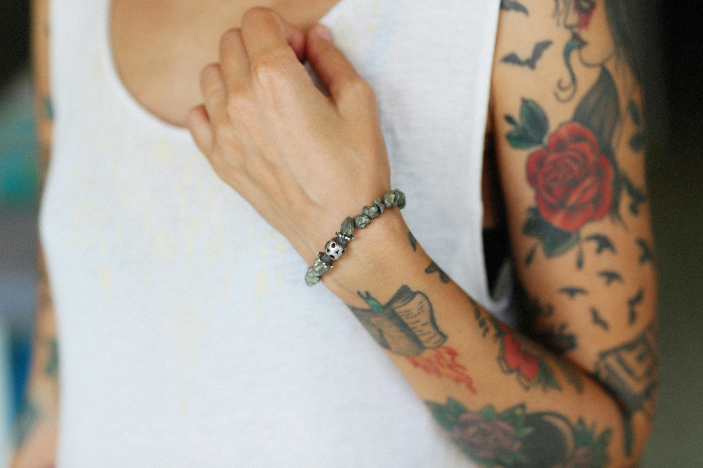 a tattooed person's arm with tattoos holding onto a flower