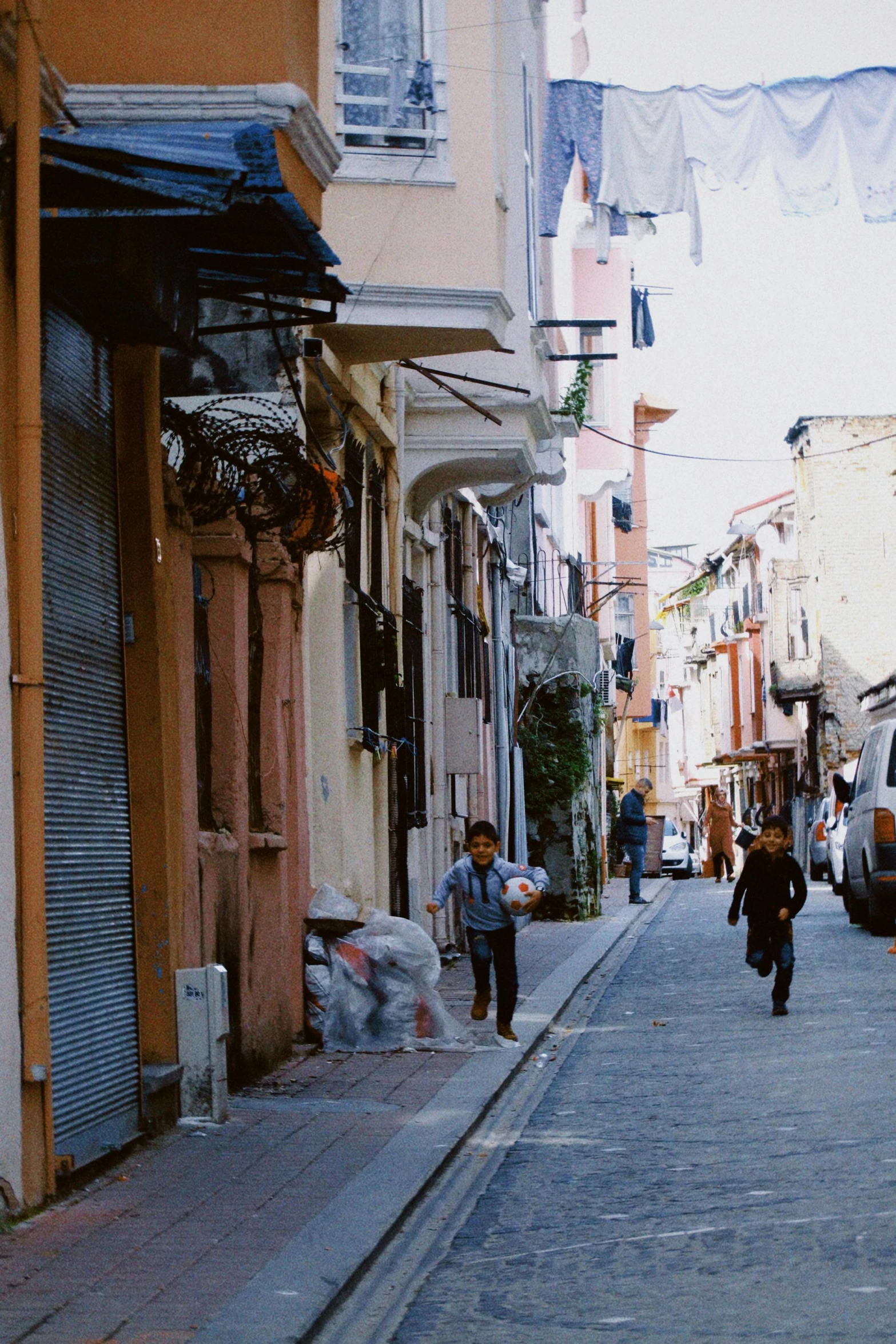 a man walking down the middle of a street past buildings