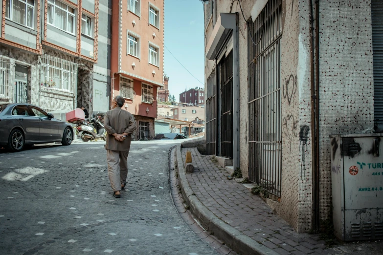 a man walking down a small cobblestone street in front of two tall buildings