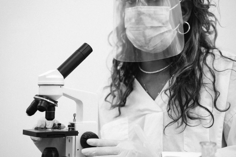 a lady holding a microscope and wearing a mask