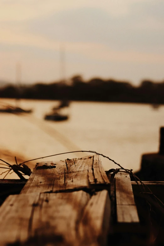 wood plank and barbed wire by water at sunset