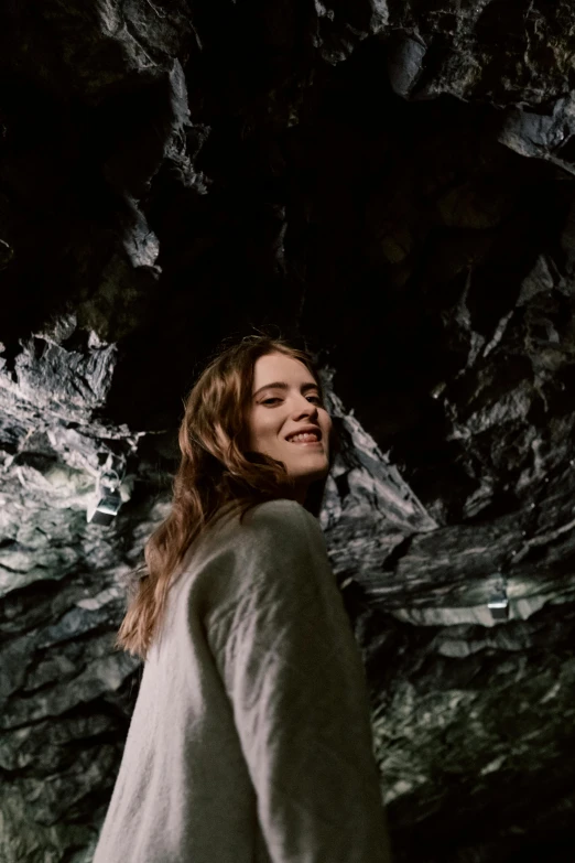 a woman standing in front of a dark cave