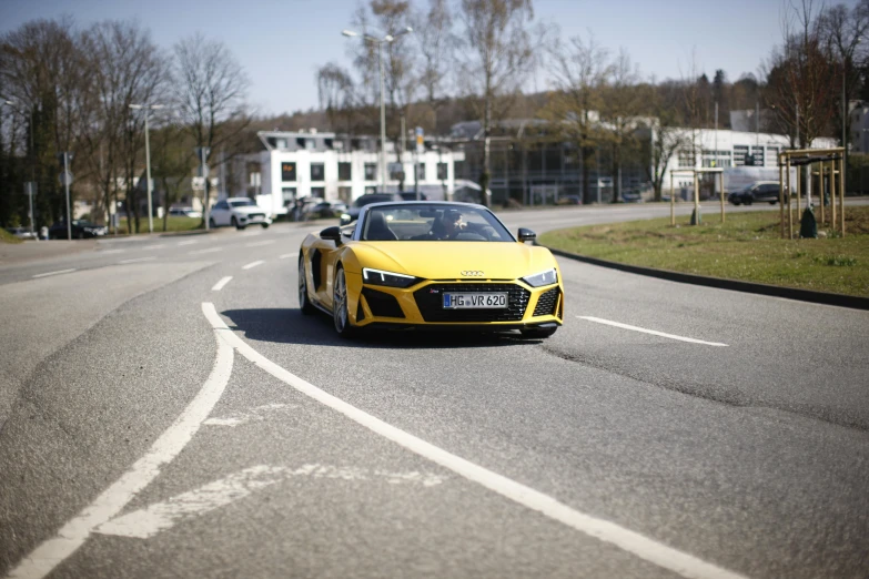 yellow sports car with open top moving down the road