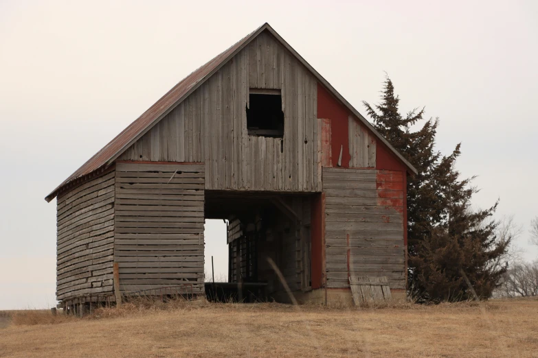 an old barn in the field next to the woods