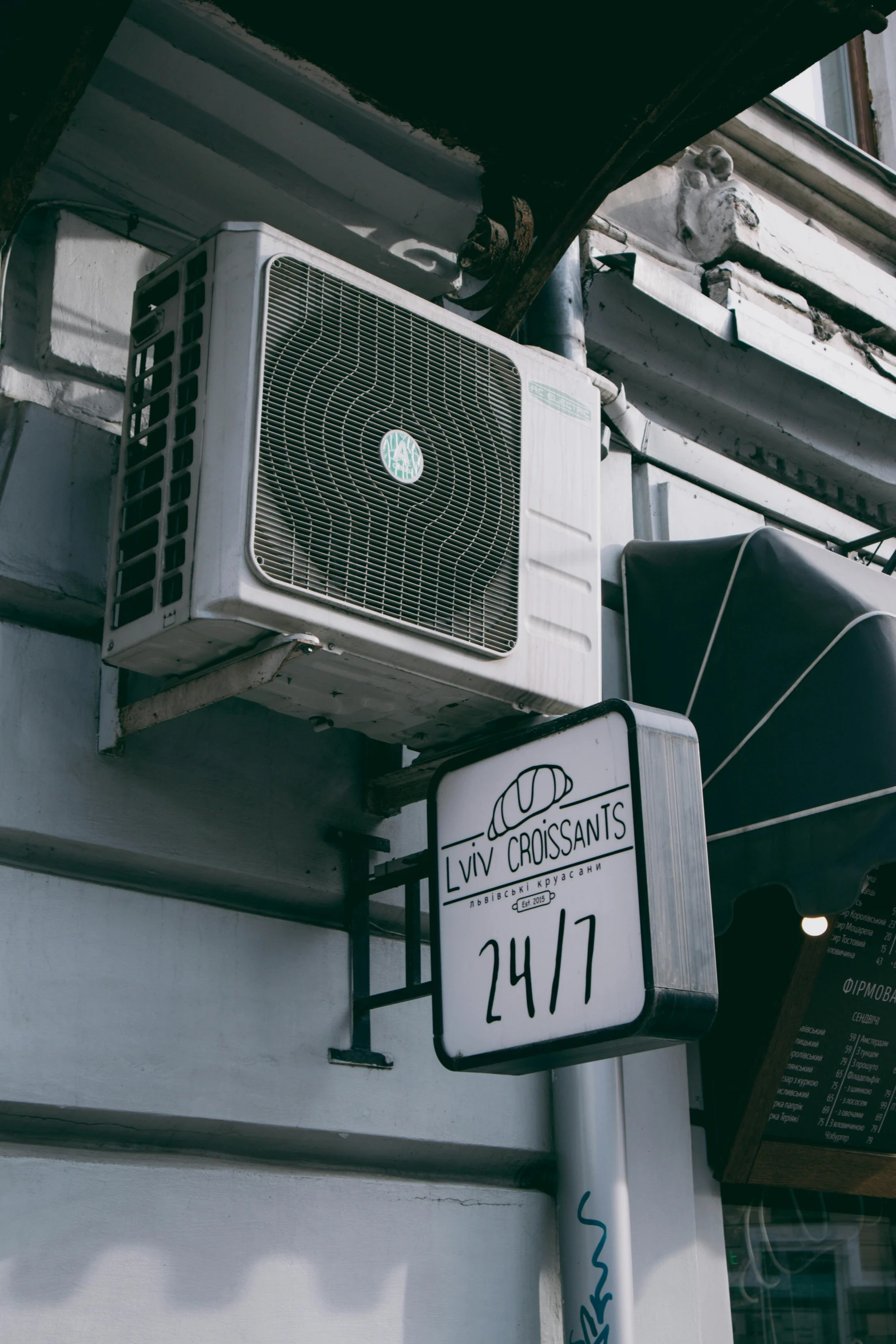 a white street sign hanging from a building