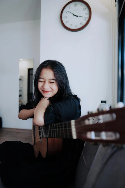 a girl is playing the guitar in her room