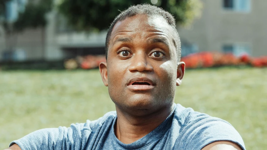 an african american man stares up as he sits in the grass