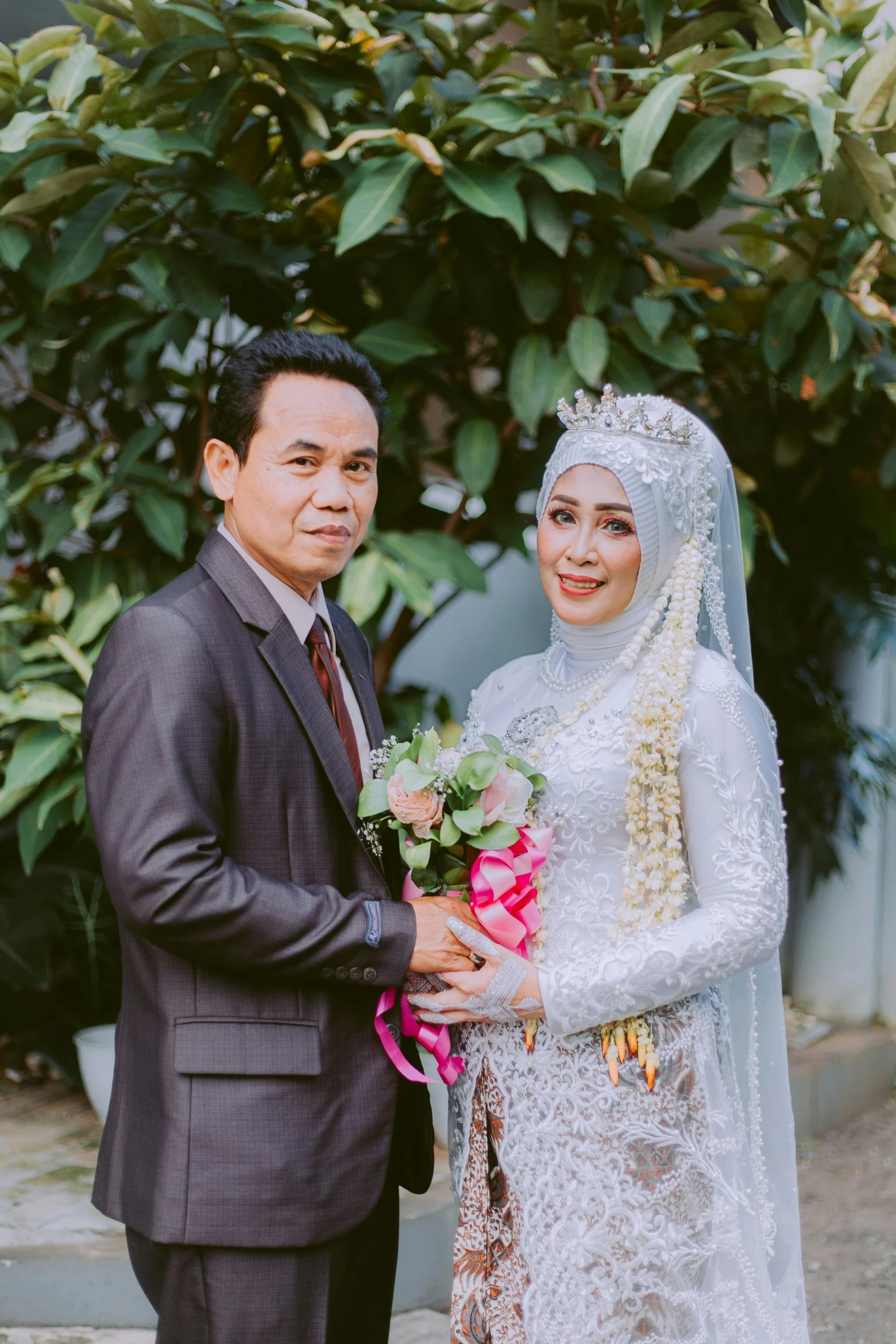 a newly married couple standing in front of some plants