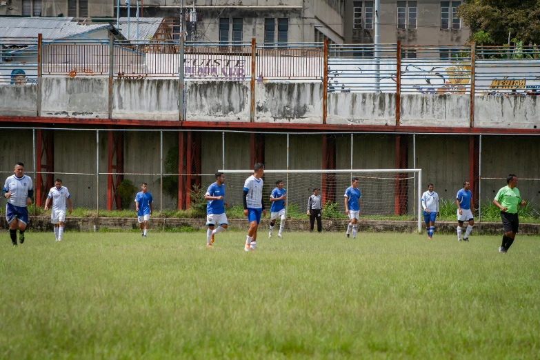 men in soccer uniforms on the field next to an old building