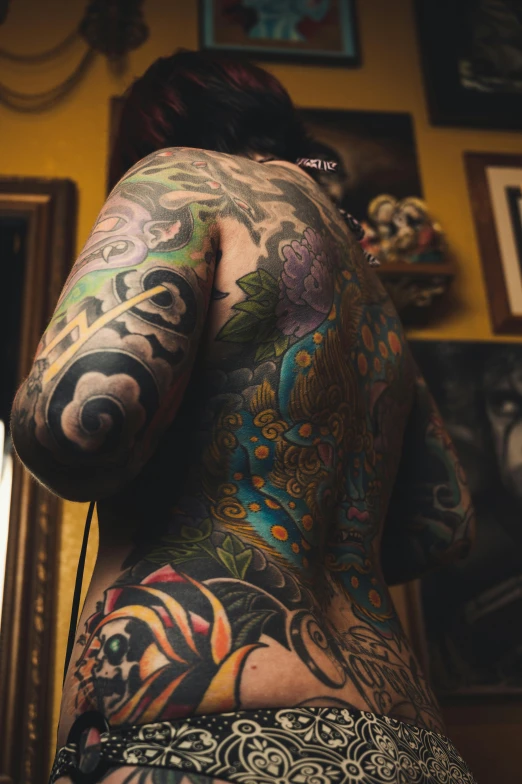 tattooed woman in a room next to many different colored pictures
