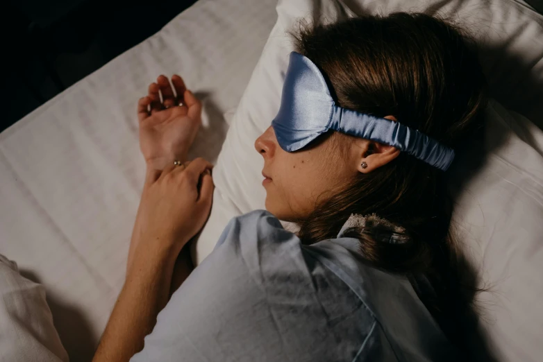 a person lying in a bed with a blue blind