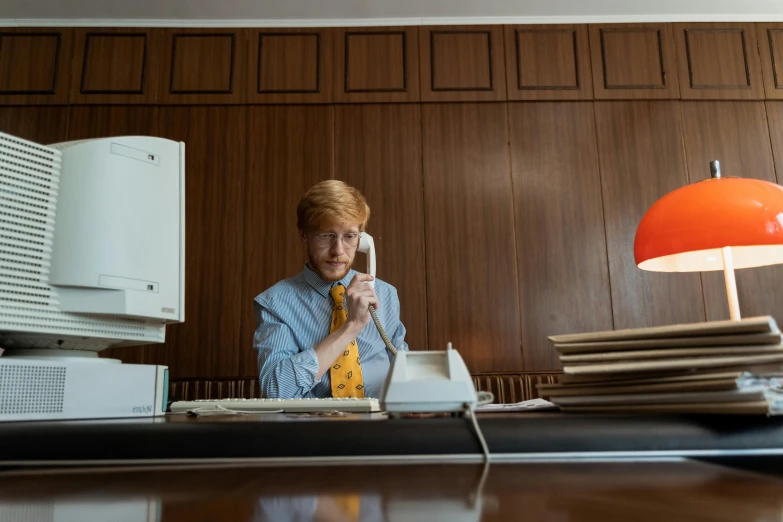 a woman at her desk, holding a phone up to her ear