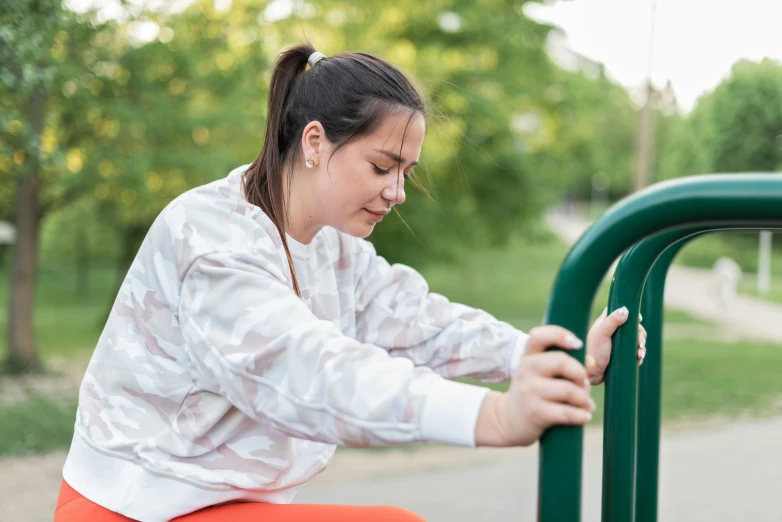 a woman in an orange skirt and a white shirt is holding onto a green rail