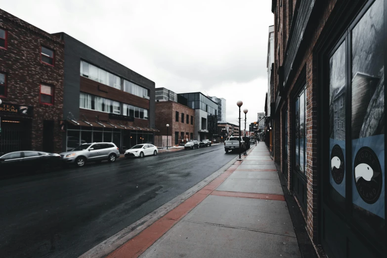 the town's sidewalk and cars are parked outside buildings