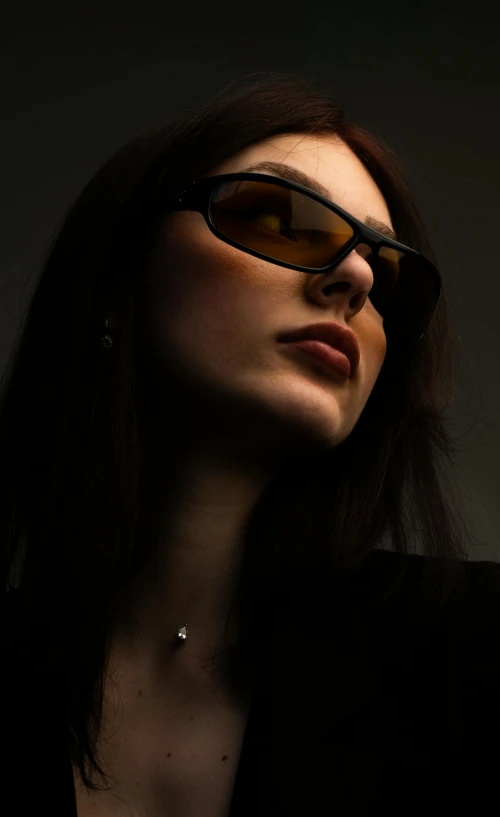 a woman in sunglasses and a black jacket with a necklace