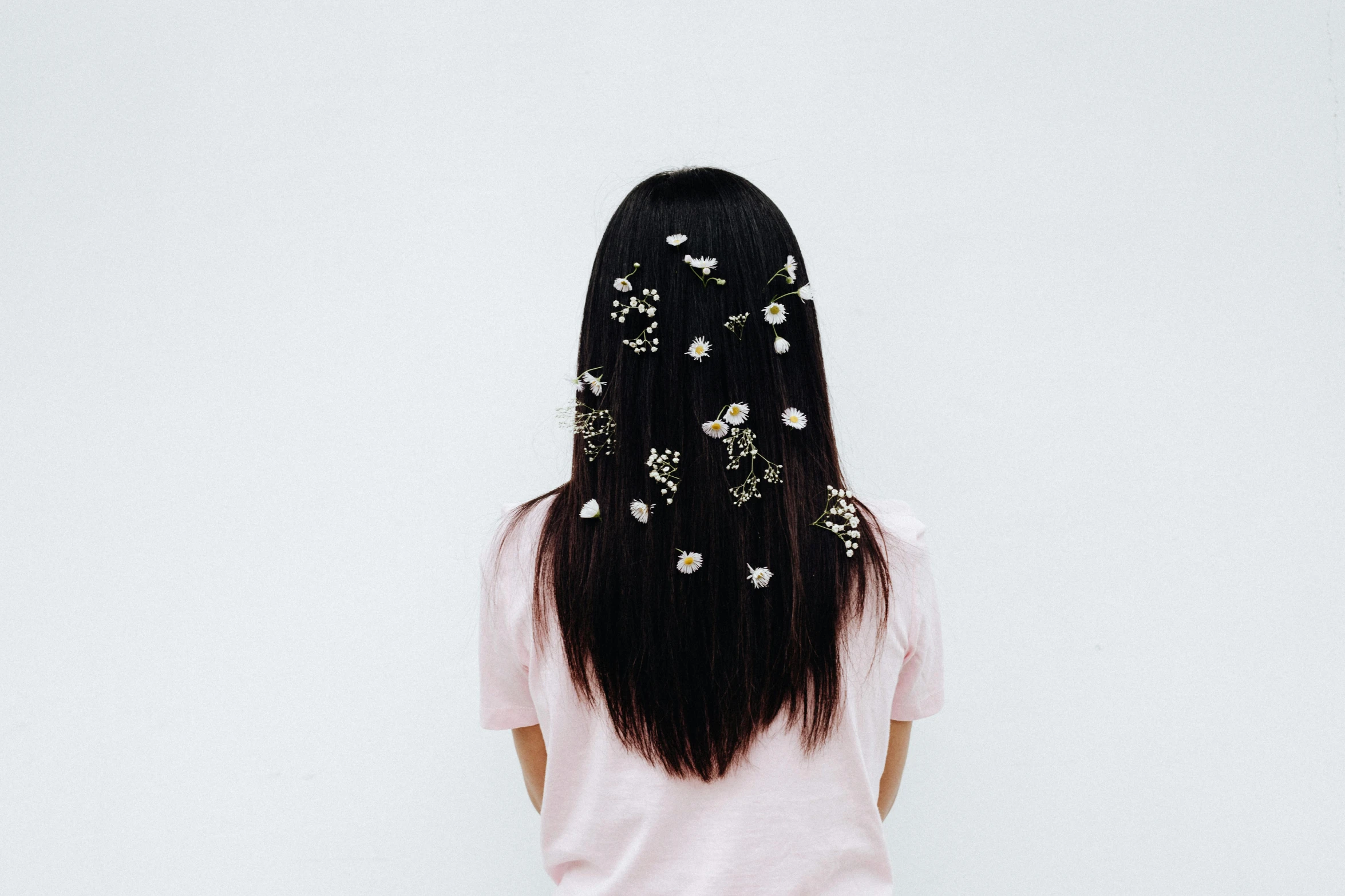 a woman with black hair wearing pink flowers