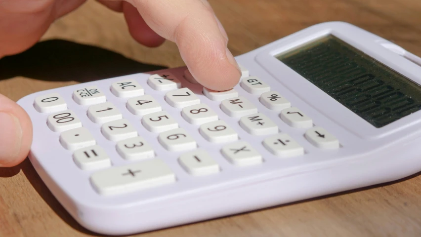the fingers of someone touching the top part of a calculator