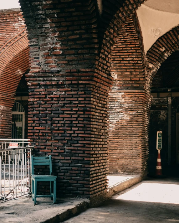 an open area with brick archways and a blue bench