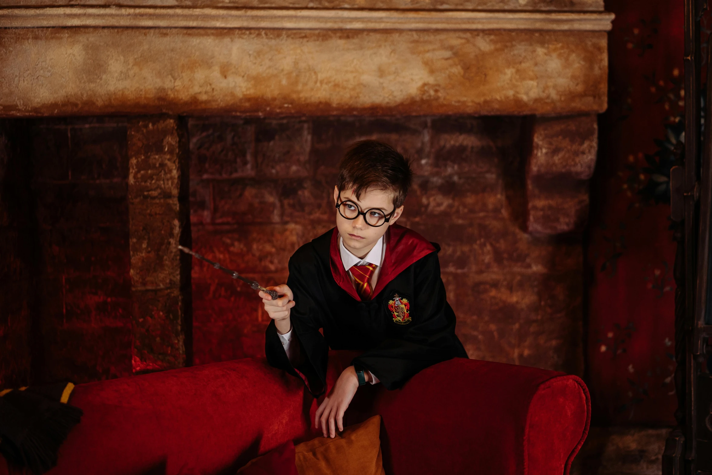 boy wearing a harry potter outfit is sitting on a red chair