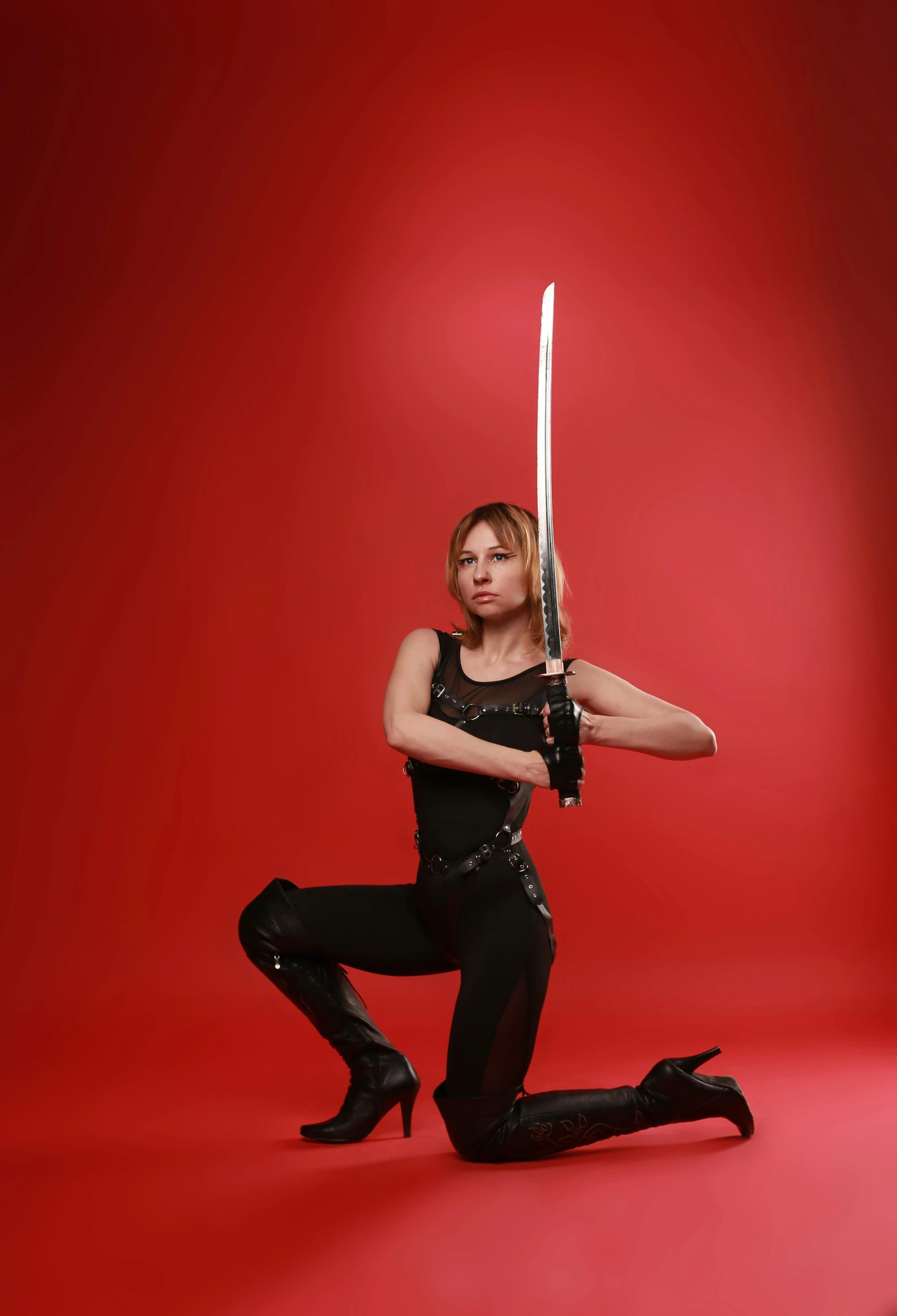 woman in leather outfit holding a sword on red background