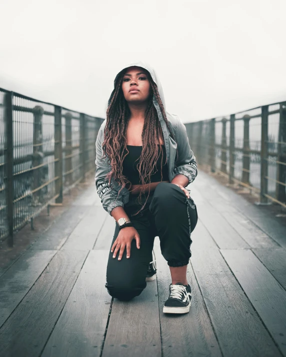 a black girl is kneeling on a bridge