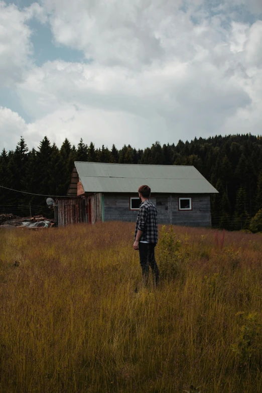 a man is in a field looking at an old barn