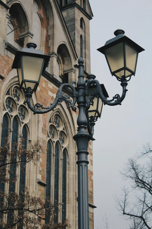 an old - fashioned light post with two light fixtures next to a church