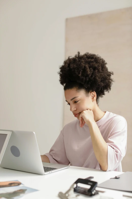 a young woman sits at a table in front of her laptop