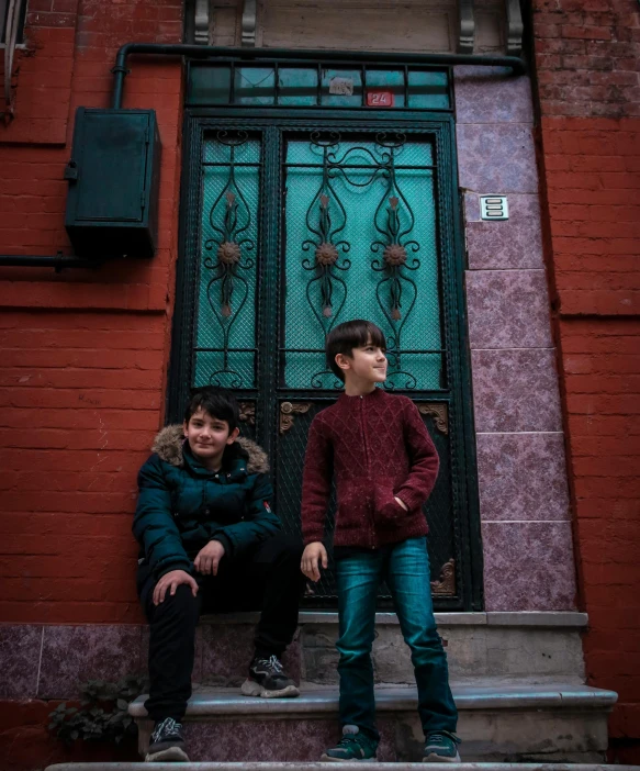 two s sitting on steps outside of a building