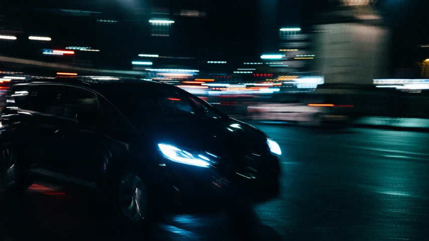 a black car is on the street at night